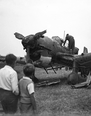 Two boys look on at the remains of a damaged airplane